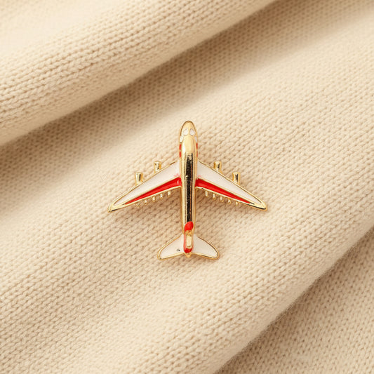 Red and white airplane brooch on a textured ivory sweater fabric