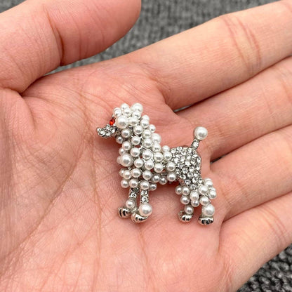a dog shaped brooch with pearl and crystal embellishment in the palm of a hand