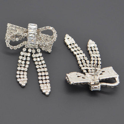 a pair of ribbon shaped rhinestone earrings showing one from the front and one from the back