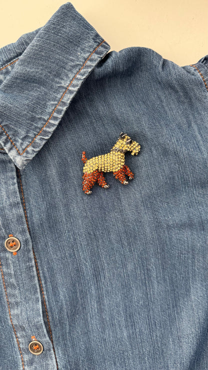 crystal encrusted schnauzer dog brooch on a denim blouse and ivory background