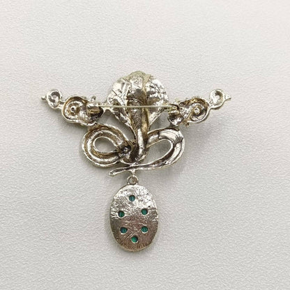 back view of serpent brooch with silver color on a light gray background