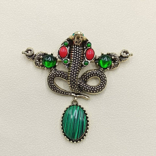 Decorative snake pendant with gemstones on a light background