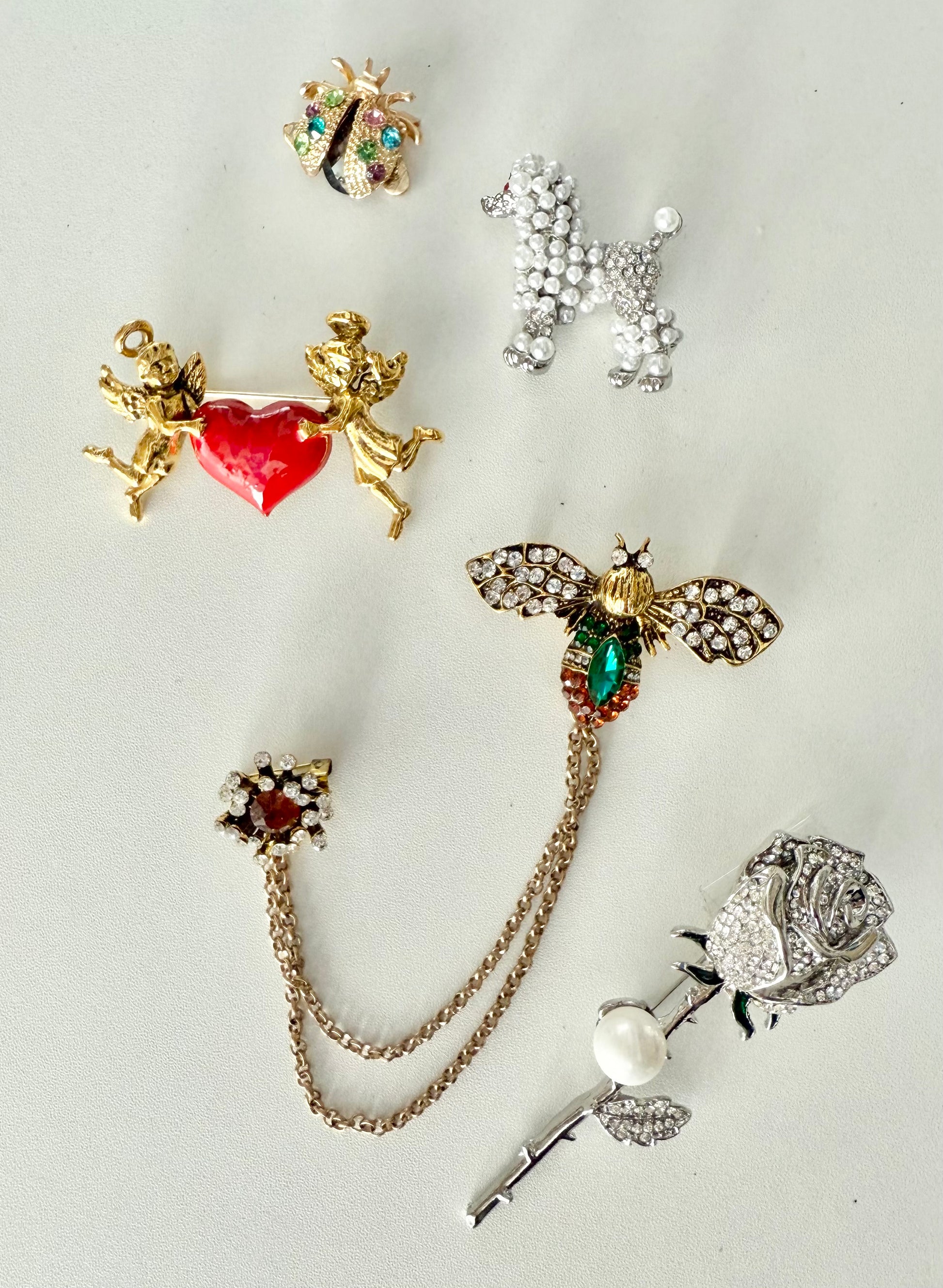 set of 5 decorative brooches against a white background