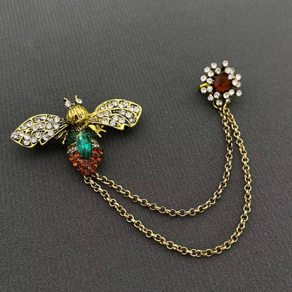 a bee and gold chain brooch against a black background