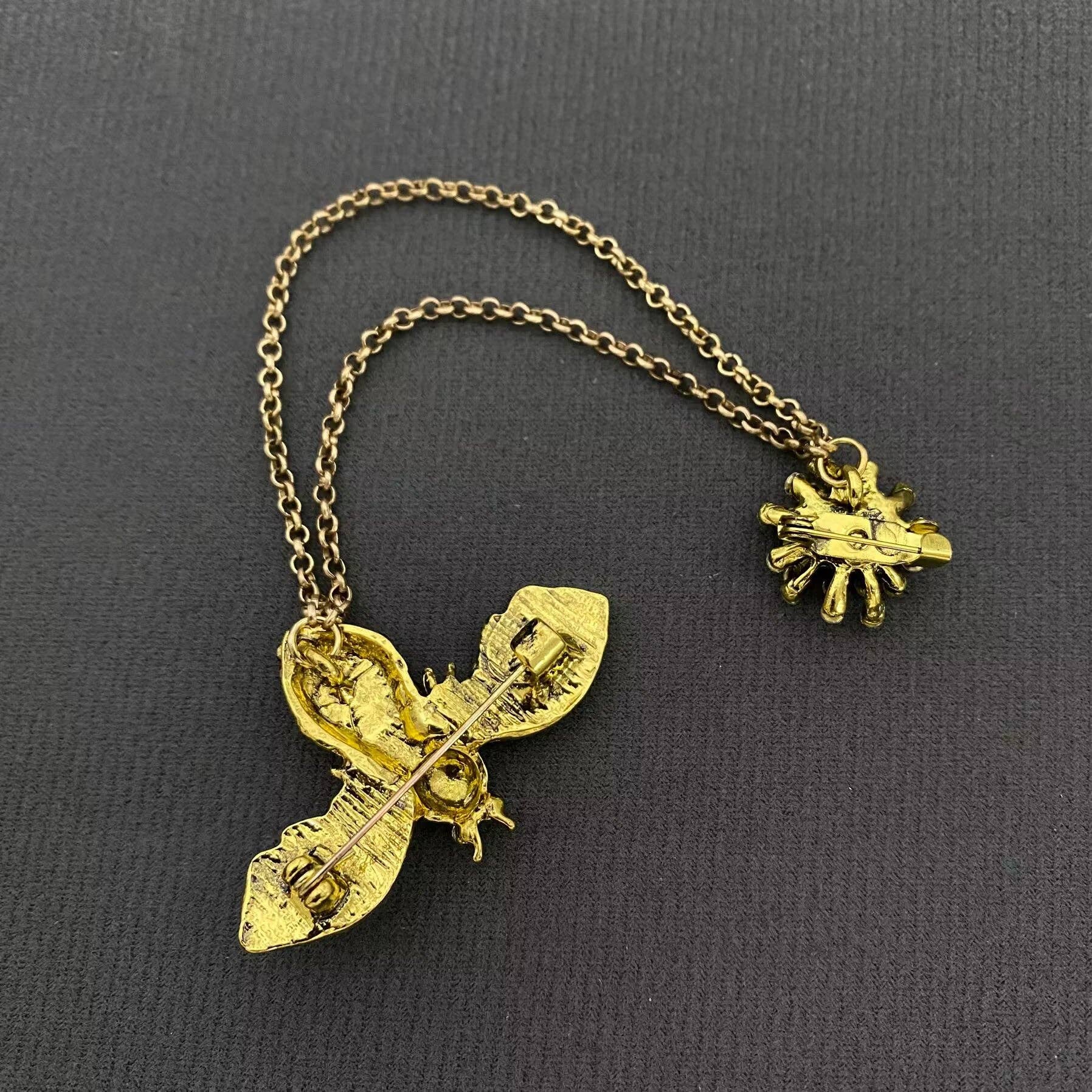 back view of a bee brooch with gold chain against a black background