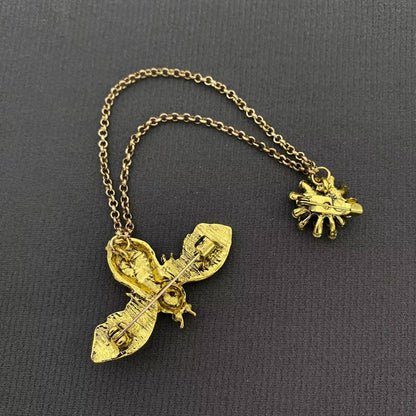 back view of a bee brooch with gold chain against a black background