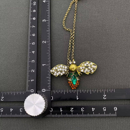 up close view of a bee brooch next to a ruler on a black background