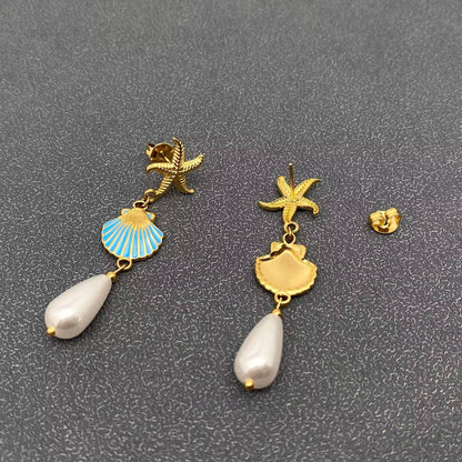 front and back view of coastal inspired gold earrings with gold starfish, enamal clam and pearl drop