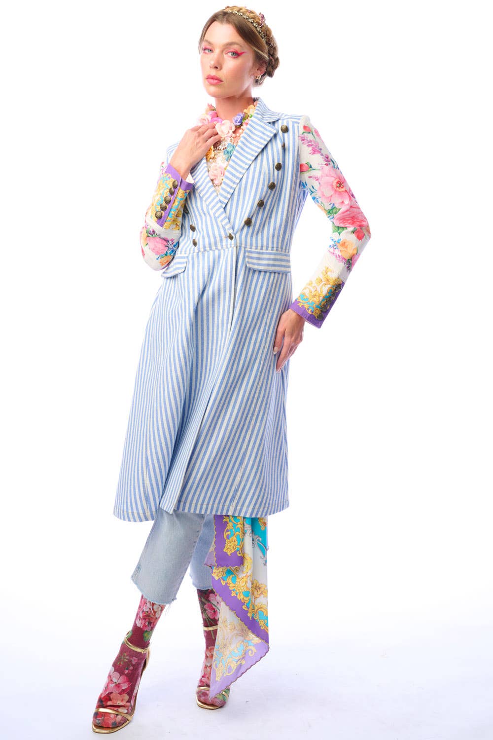 Woman wearing a blue and white striped coat with colorful floral print sleeves and antique gold button closure on a white background