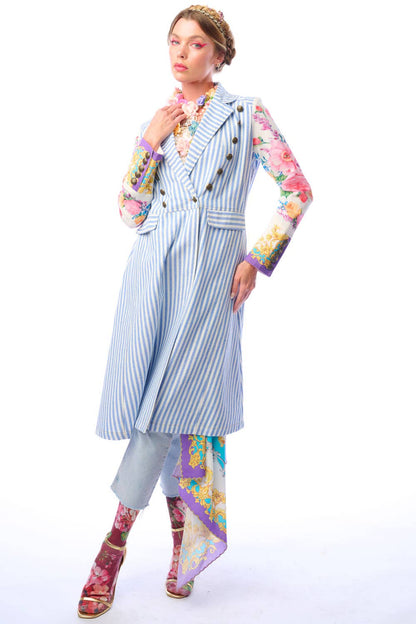 Woman wearing a blue and white striped coat with colorful floral print sleeves and antique gold button closure on a white background