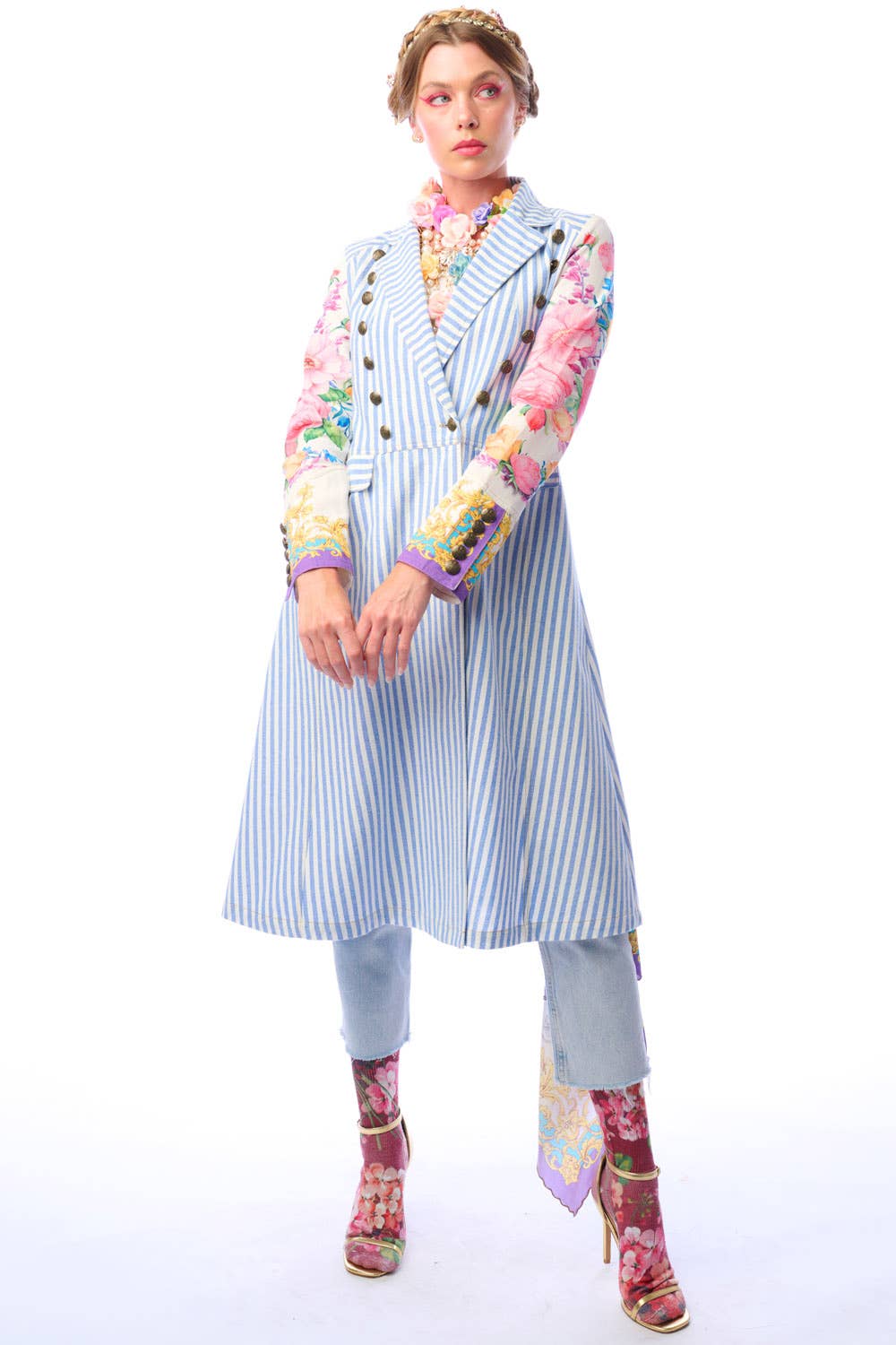 Woman wearing a blue and white striped coat with colorful floral print sleeves and antique gold button closure on a white background