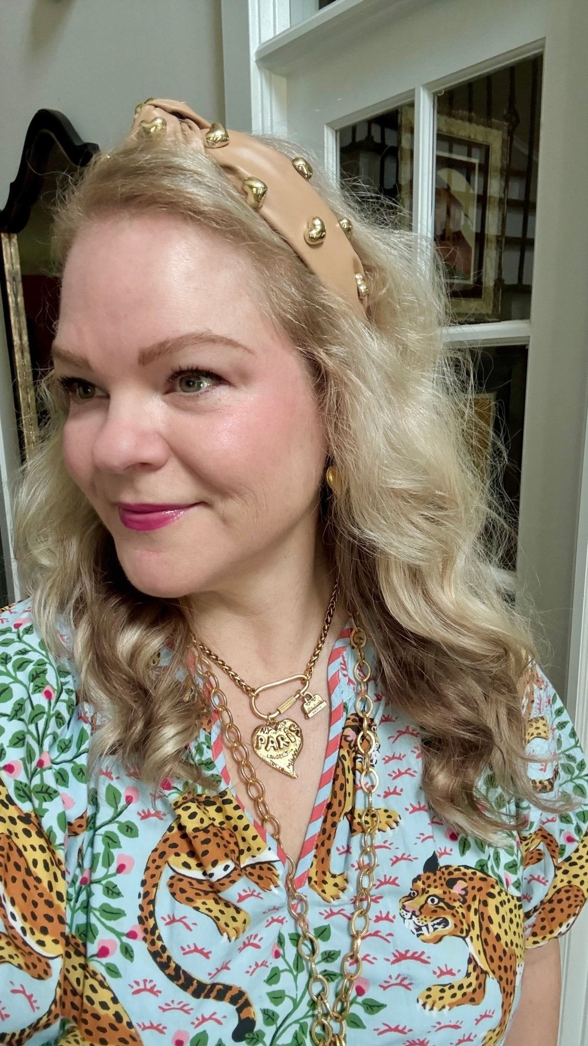 Woman wearing a patterned blouse with animal designs and a tan headband indoors.