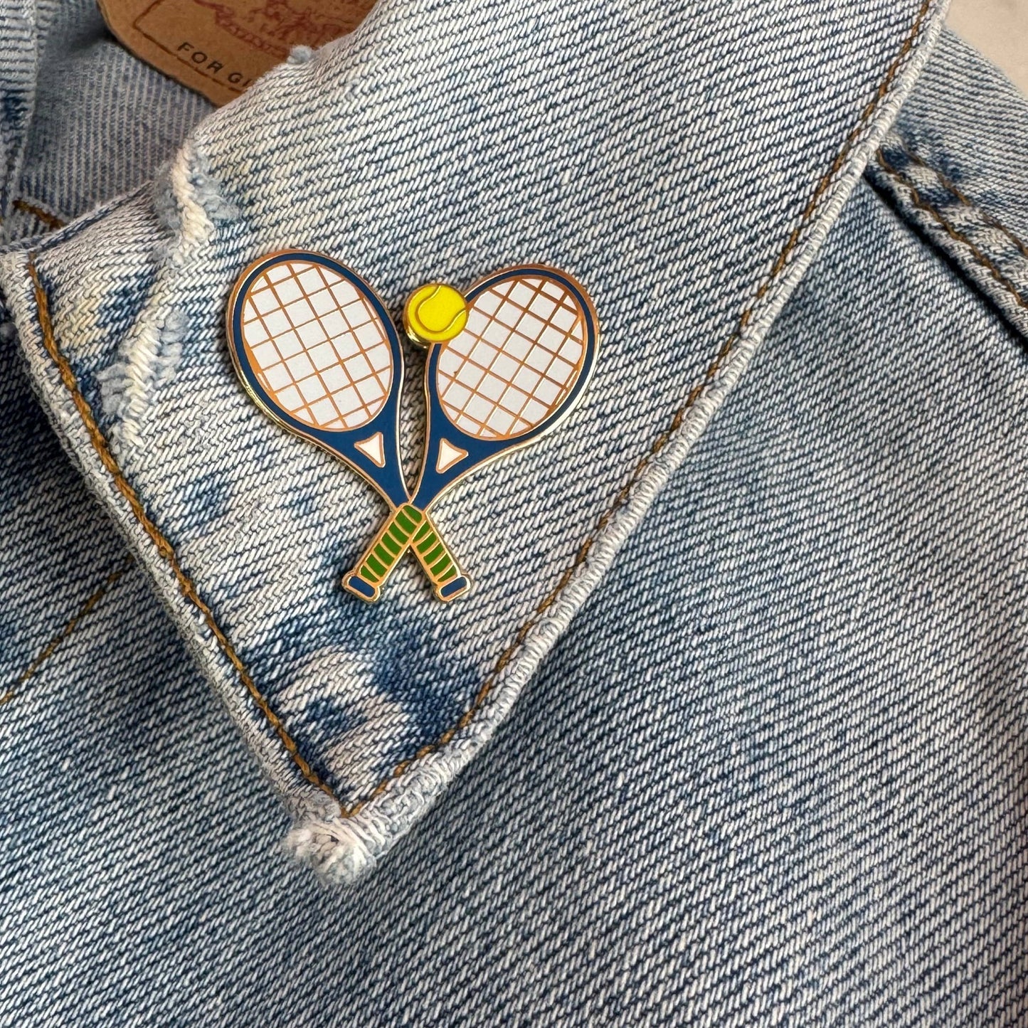 Tennis racket-shaped pin on a denim jacket