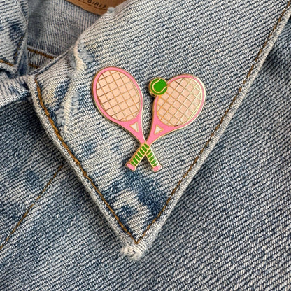 Pink tennis racket and ball enamel pin on a denim jacket