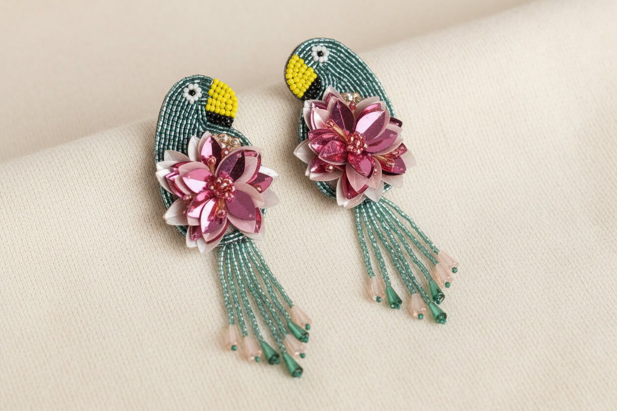 a pair of toucan and floral beaded dandle earrings against a white background