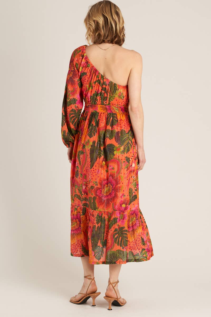 back view of woman wearing a one shoulder orange tropical print dress and strappy heels