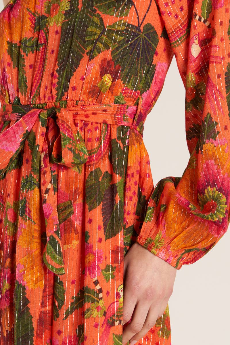 close up view of woman wearing a one shoulder orange tropical print dress 