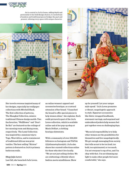 Woman in a magazine feature wearing an orange one shoulder tropical print dress sitting on a bed