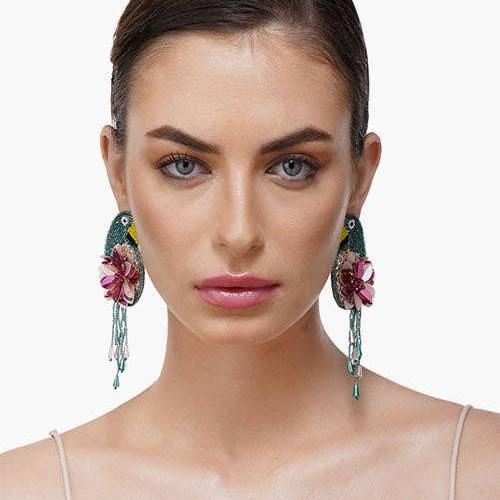 woman wearing tucan and floral beaded dandle earrings