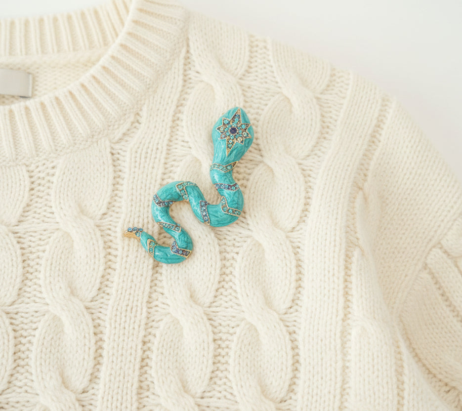 Turquoise snake brooch on an ivory sweater 