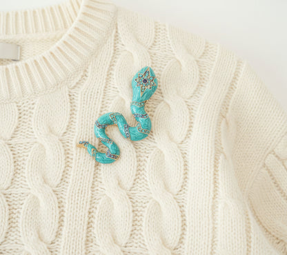 Turquoise snake brooch on an ivory sweater 