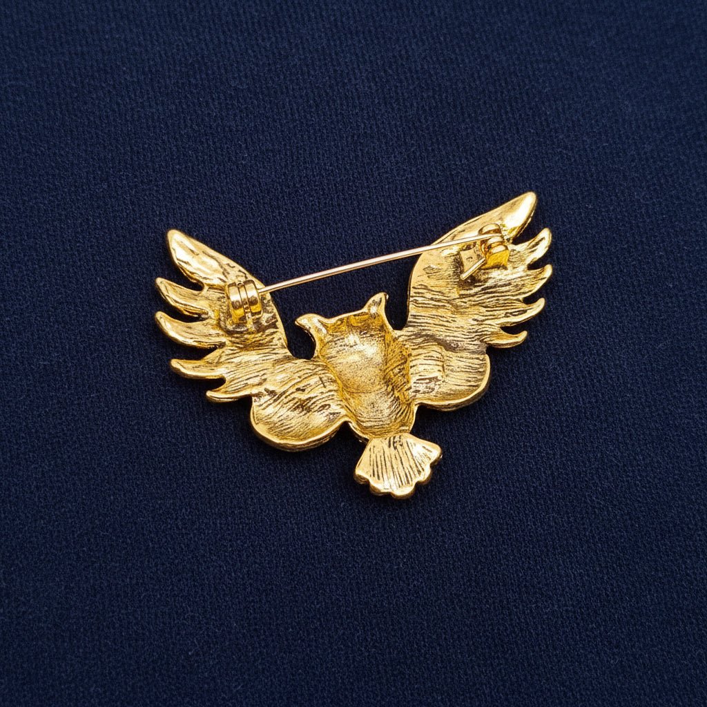 back view of an owl brooch showing the pin closure on a navy fabric background