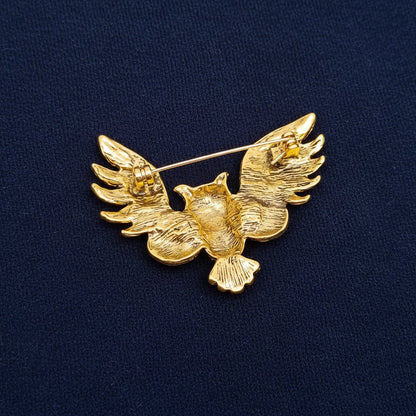 back view of an owl brooch showing the pin closure on a navy fabric background