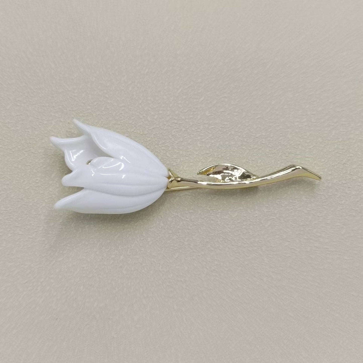 White tulip-shaped brooch on a beige background