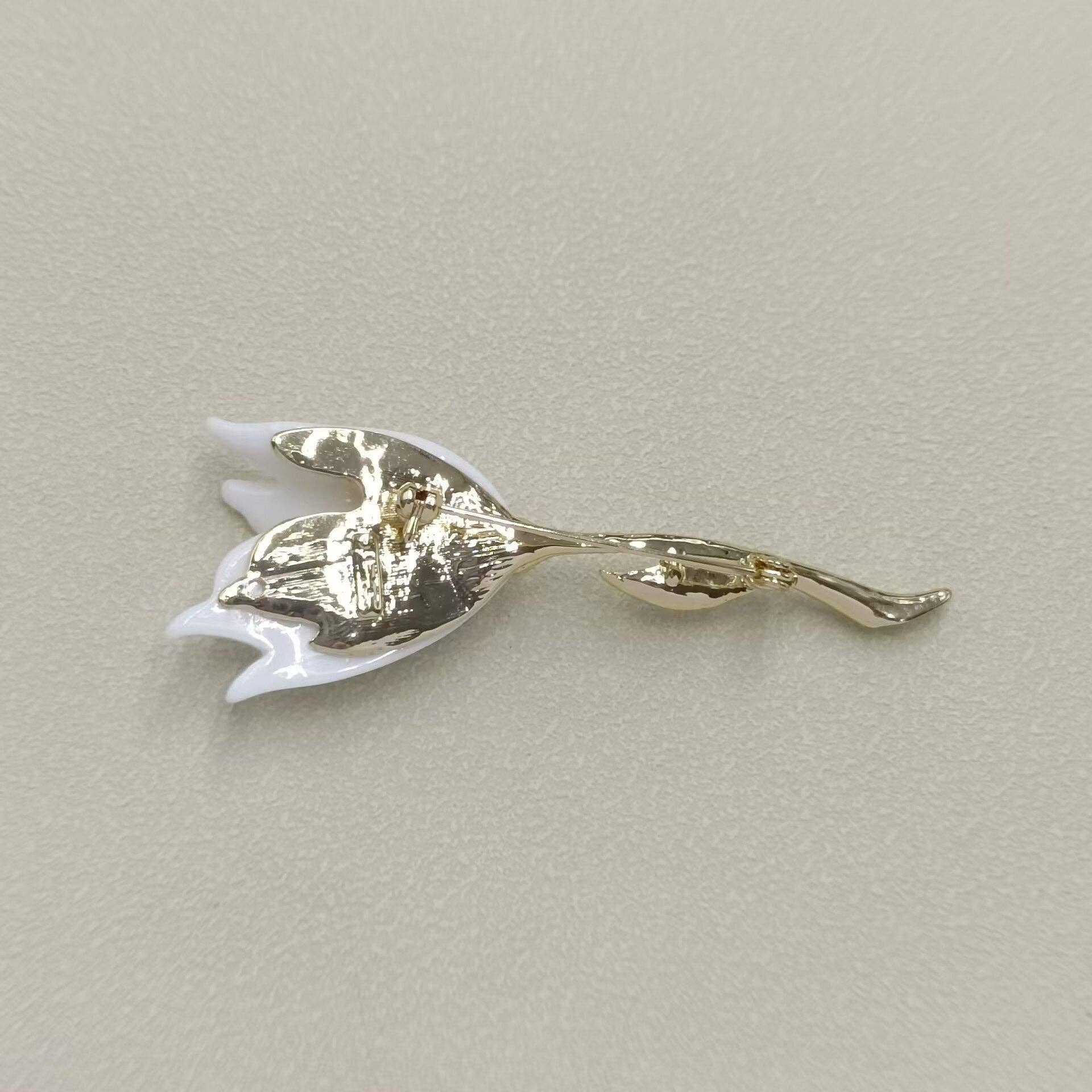 Gold tulip-shaped brooch on a light gray background