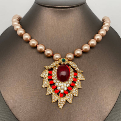Pearl necklace with a decorative pendant featuring a red gemstone on a mannequin.