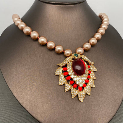 Pearl necklace with a decorative pendant featuring a red gemstone on a mannequin.