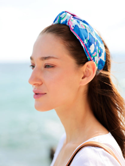 Woman wearing watercolor blue and pink headband with a beach background