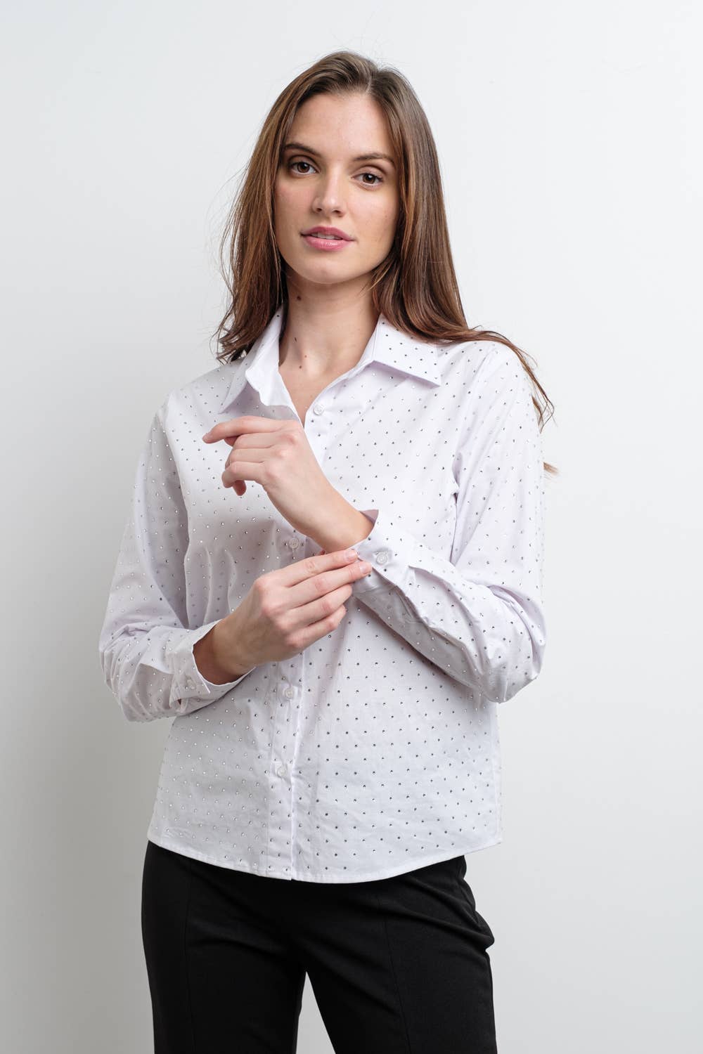 Woman wearing a white blouse with a rhinestone pattern against a plain background
