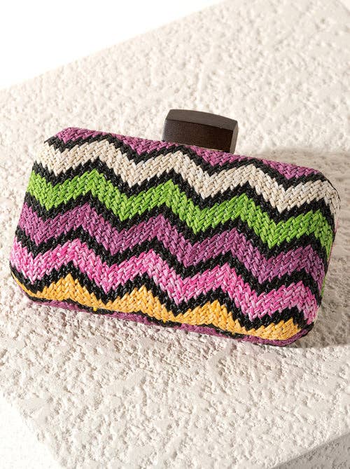 Colorful zigzag patterned clutch bag on a textured ivory surface.