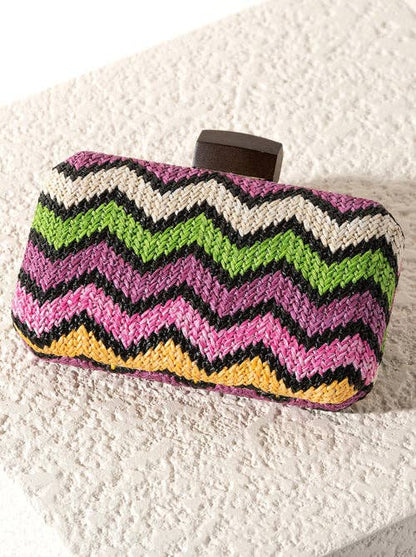 Colorful zigzag patterned clutch bag on a textured ivory surface.