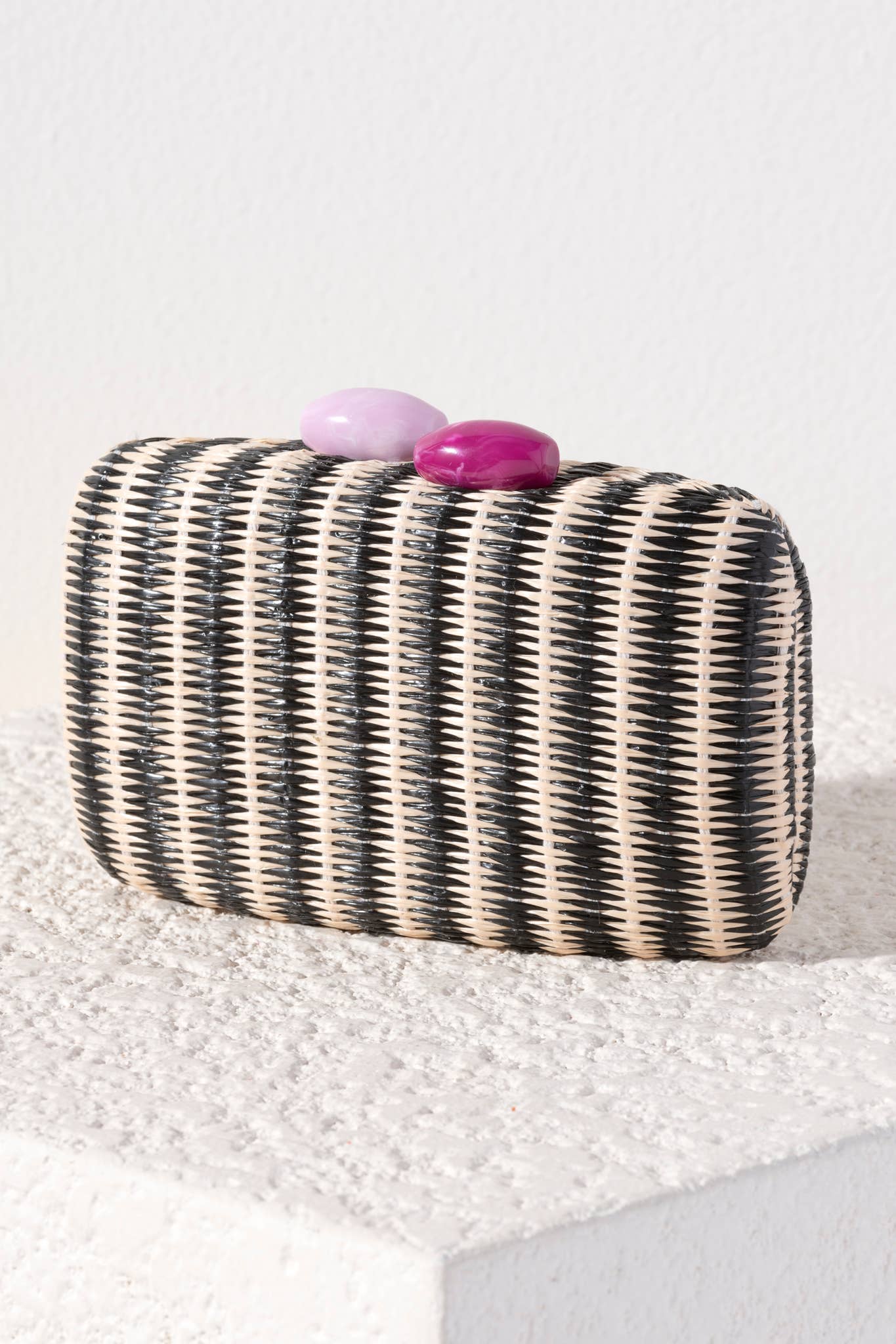 Black and white striped clutch with pink and purple stones on a white background